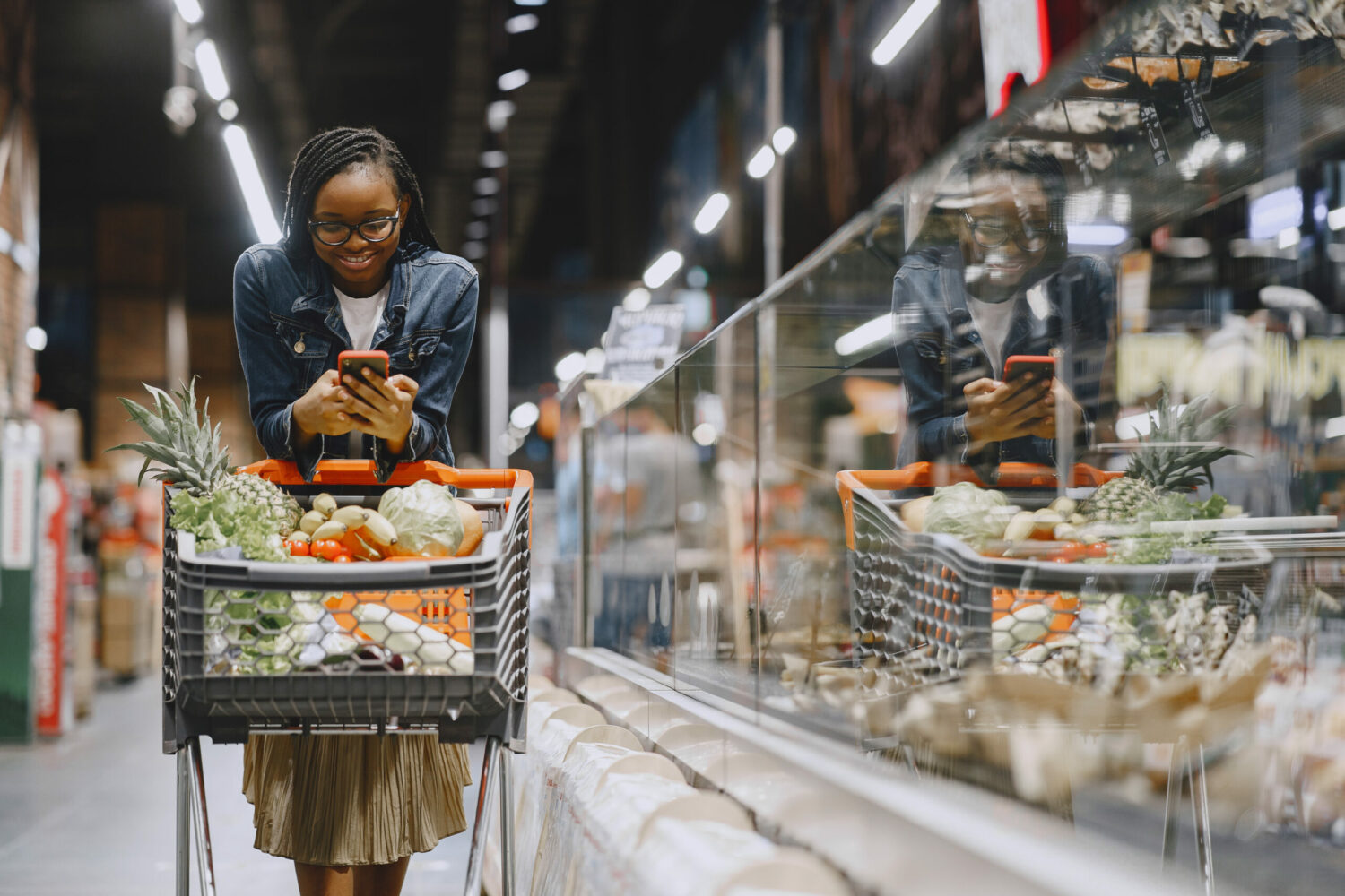 Femme faisant ses courses au supermarché et regardant son téléphone